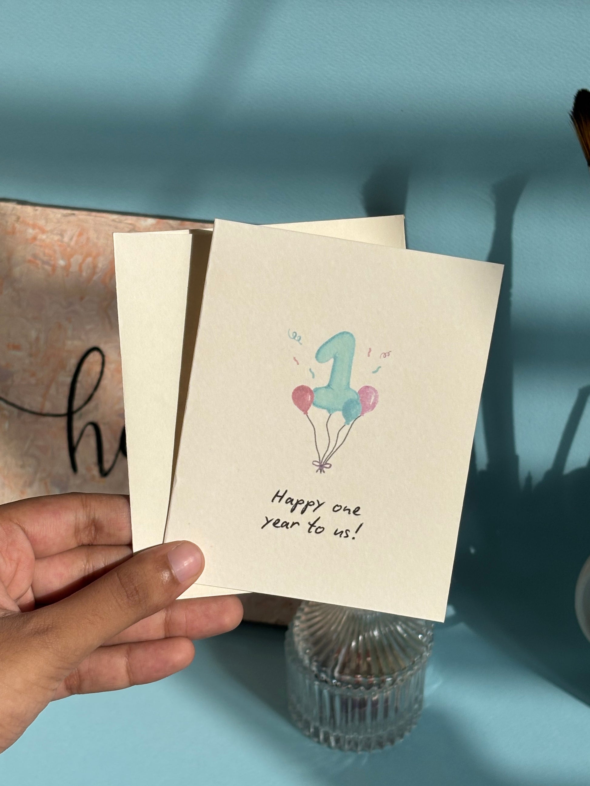 Happy one year anniversary greeting card with watercolor number one and balloons