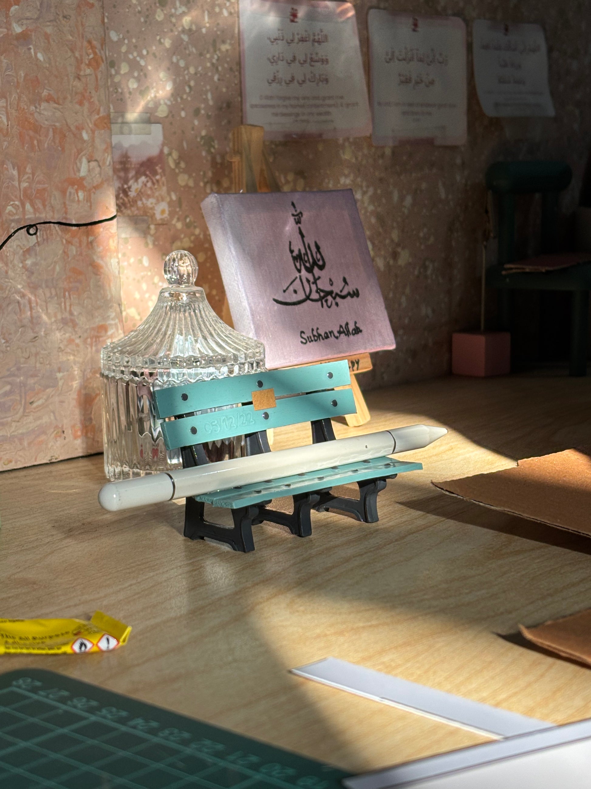 Turquoise miniature bench pen holder styled on a craft desk with a white pen