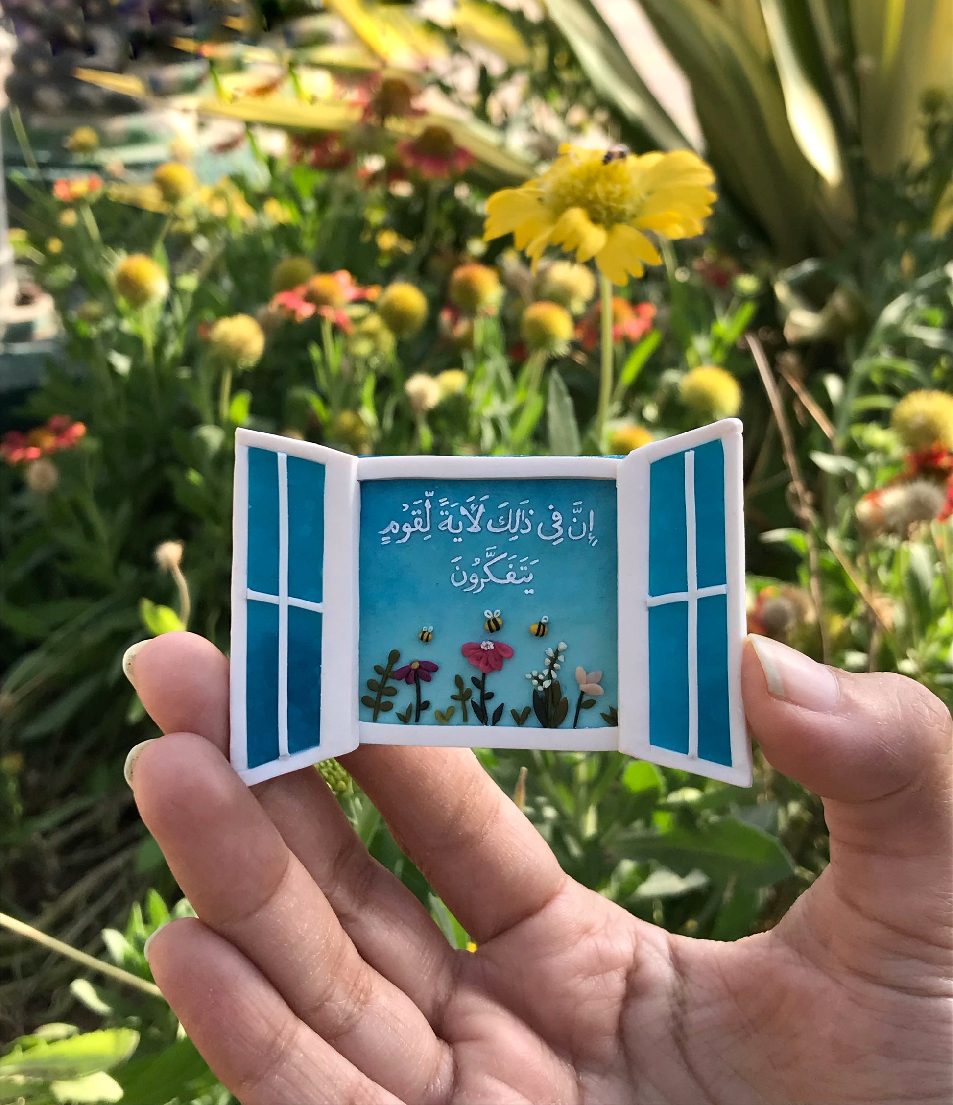 Handmade blue open-window fridge magnet with Quranic reminder, flowers and bees